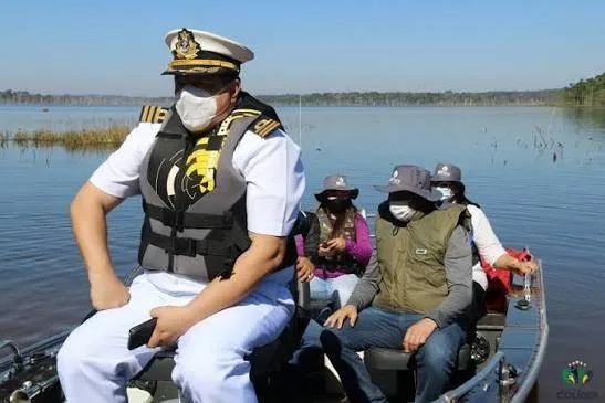 Alessandro Fajard, de farda branca e colete salva-vidas, numa lancha em rio de Mato Grosso